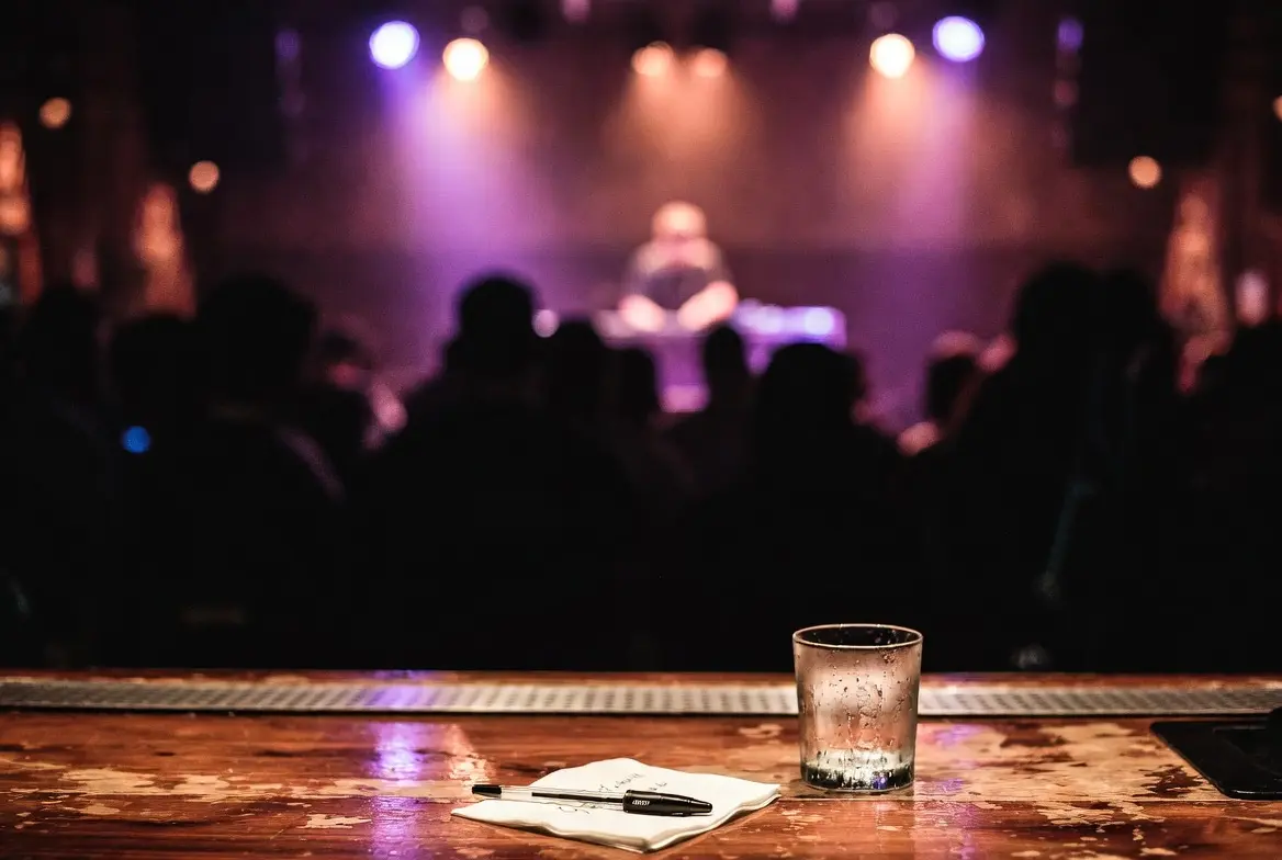An Austin music venue interior at night with a cocktail napkin in the foreground bearing illegible handwriting.